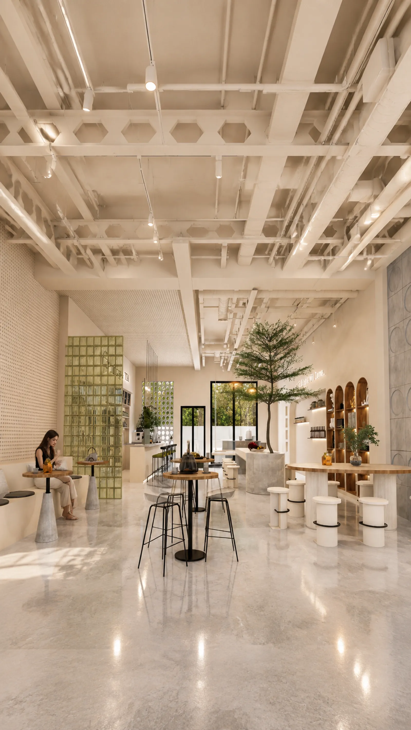 Vista vertical de cafetería con mujer sentada en mesa comunal, mesas auxiliares con repostería y nichos arqueados decorativos al fondo.